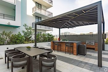 Outdoor grilling station with two BBQ grills and ample seating under a pergola at Hollywood Heights on the Boulevard Luxury Apartments in Hollywood, FL